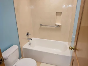 a bright white alcove tub sits within a tiled enclosure this bathing vessel often called a soak tub or wash basin features chrome fixtures and a built in wall niche photo 1